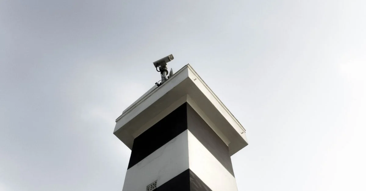 Une tour de surveillance moderne équipée d'une caméra CCTV sur un ciel dégagé, montrant la sécurité et la technologie.