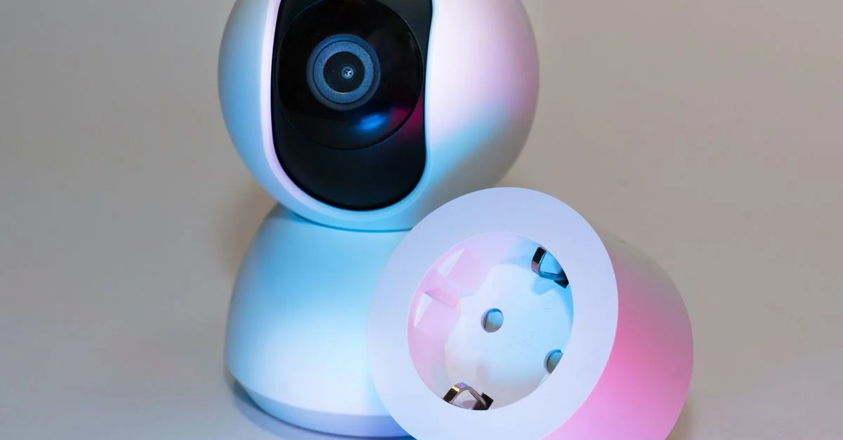 Caméra de sécurité pour maison intelligente et prise électrique sur un fond neutre.